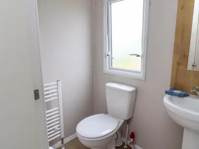 a bathroom with a toilet and a sink and a window at Windermere Lodge in Morecambe