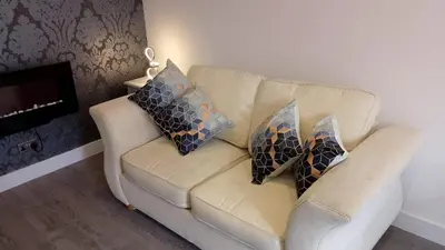 a couch with three pillows on it in a living room at St Annes Lodge Garden Flat AWARD WINNING HOSTS in Lytham St Annes