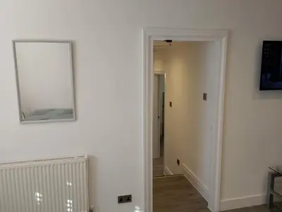 a hallway with a mirror on a white wall at St Annes Lodge Garden Flat AWARD WINNING HOSTS in Lytham St Annes