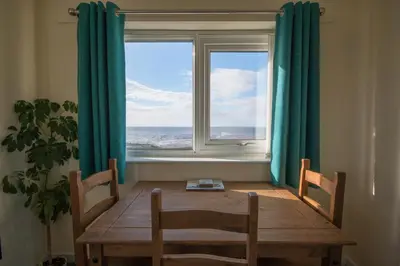 a dining room with a table and two chairs and a window at Half Moon Bay in Heysham