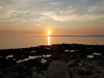 a sunset on the shore of a body of water at Half Moon Bay in Heysham