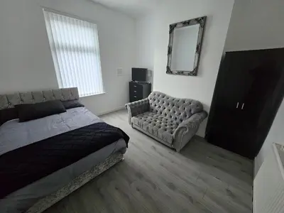 a bedroom with a bed and a couch and a mirror at Anfield Guest House Sleeps 5 in Liverpool