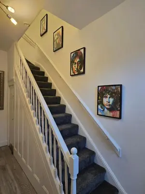 a staircase with three paintings on the wall at Anfield Guest House Sleeps 5 in Liverpool