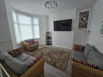 a living room with two couches and a flat screen tv at Anfield Guest House Sleeps 5 in Liverpool
