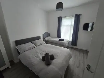 a small bedroom with two beds and a window at Anfield Guest House Sleeps 5 in Liverpool