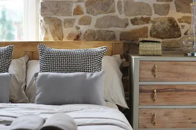 a bedroom with a bed with pillows and a stone wall at Home in Chorley, Lancashire in Chorley