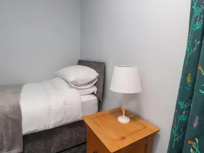 a bedroom with a bed and a table with a lamp at 3 Cowper Place in Clitheroe