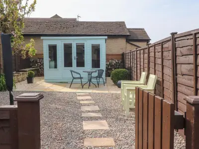 a backyard with a shed with chairs and a table at 3 Cowper Place in Clitheroe