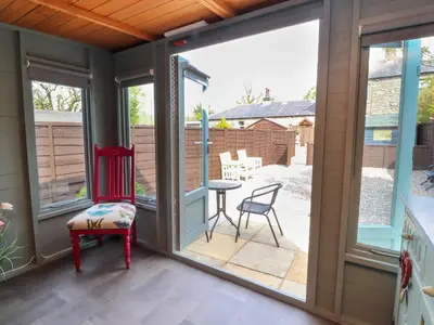 a screened in porch with a red chair and a table at 3 Cowper Place in Clitheroe