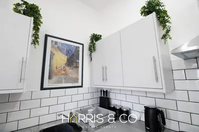 a kitchen with white tiled walls and white cabinets at Roundtree & Berry - Fleetwood in Fleetwood