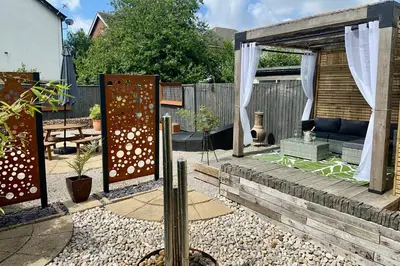 a garden with a wooden pergola and a patio at Charles Alexander Short Stay - Derbe House in Lytham St Annes