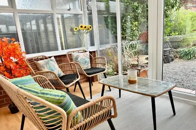 a screened in porch with wicker chairs and a table at Charles Alexander Short Stay - Derbe House in Lytham St Annes