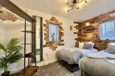 two beds in a room with wooden walls at Charles Alexander Short Stay - Derbe House in Lytham St Annes