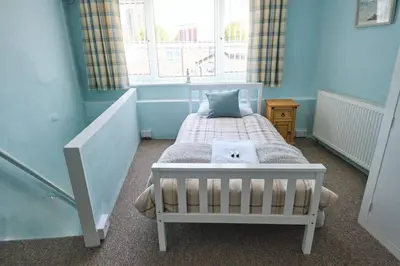 a bedroom with a bed with a cat pillow on it at Olivia Cottage - a Home From Home by the Sea in Morecambe