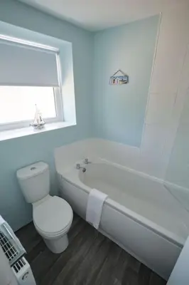 a white bathroom with a toilet and a bath tub at Olivia Cottage - a Home From Home by the Sea in Morecambe