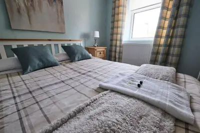 a bedroom with a bed with a blanket and a window at Olivia Cottage - a Home From Home by the Sea in Morecambe