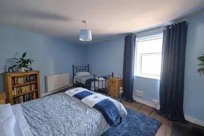 a blue bedroom with a bed and a window at Evie Cottage - The peaceful Retreat in Morecambe