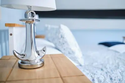 a silver lamp on a wooden table next to a bed at Evie Cottage - The peaceful Retreat in Morecambe