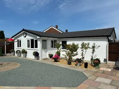 a white house with potted plants in a driveway at The Hideaway in Ainsdale