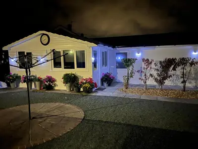 a house with a clock on the side of it at night at The Hideaway in Ainsdale