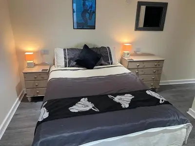 a bedroom with a bed with two dressers and two lamps at The Hideaway in Ainsdale