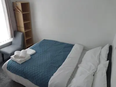a bed with two towels and a chair in a room at Pinnacle Hotel & Suites formerly Jean Martyn Hotel Near Central Blackpool, Near Beach & Attractions in Blackpool
