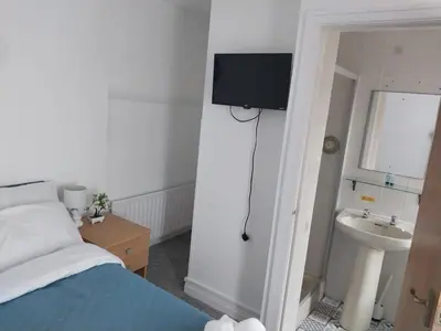 a bedroom with a bed and a sink and a tv at Pinnacle Hotel & Suites formerly Jean Martyn Hotel Near Central Blackpool, Near Beach & Attractions in Blackpool