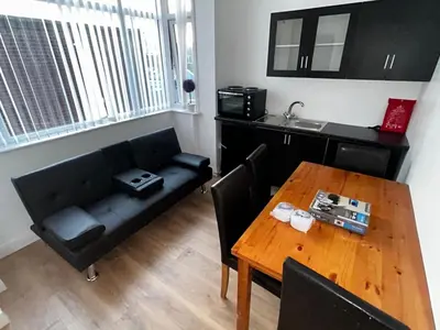 a living room with a black couch and a table at Pinnacle Hotel & Suites formerly Jean Martyn Hotel Near Central Blackpool, Near Beach & Attractions in Blackpool