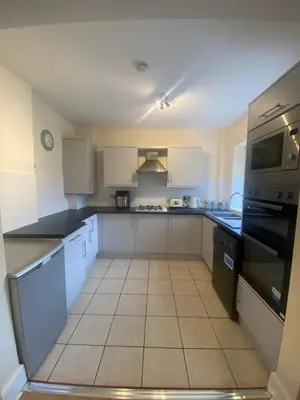 a large kitchen with white cabinets and black appliances at Lovely 3 bed house in Crosby in Crosby