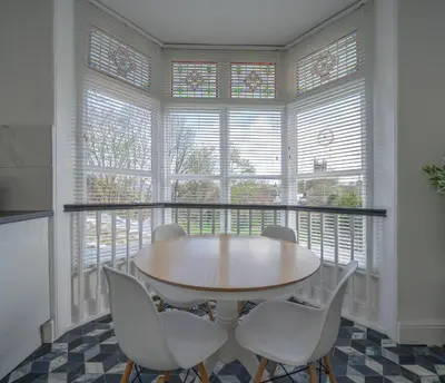 a dining room with a table and chairs and windows at Casbah Coffee Club Suites in West Derby