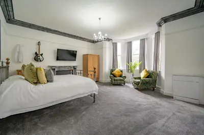 a large bedroom with a bed and two chairs at Casbah Coffee Club Suites in West Derby