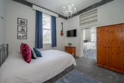 a bedroom with a large white bed and a chandelier at Casbah Coffee Club Suites in West Derby