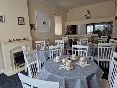 a dining room with tables and chairs and a fireplace at Glendor Hotel in Blackpool