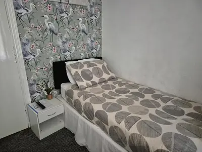 a small bedroom with a bed and a wall at Glendor Hotel in Blackpool