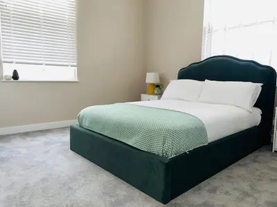 a bedroom with a large bed with a green headboard at Gorgeous Quarter House Apartment in Liverpool