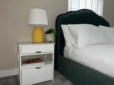 a bed with a white night stand with a lamp on it at Gorgeous Quarter House Apartment in Liverpool