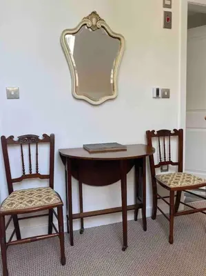 a table with two chairs and a mirror on a wall at Helens Haven First floor apartment via stairs in Preston