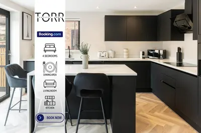 a kitchen with black cabinets and a table and chairs at Luxury 4BDR House By Torr Property Group Short Lets & Serviced Accommodation With Free Gated Secure Parking & Private Patio Garden Liverpool in Liverpool