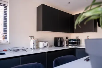 a kitchen with black cabinets and appliances on a counter at Luxury 4BDR House By Torr Property Group Short Lets & Serviced Accommodation With Free Gated Secure Parking & Private Patio Garden Liverpool in Liverpool