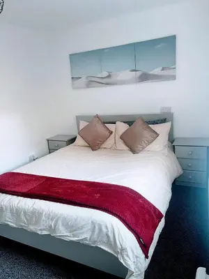 a bedroom with a bed with a red blanket on it at Bay Wind Apartment in Morecambe
