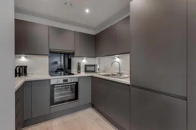 a kitchen with dark grey cabinets and a sink at Huge Long Stay Savings! City View Balcony Penthouse in Liverpool