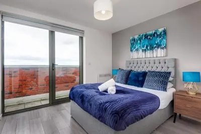 a bedroom with a bed and a large window at Huge Long Stay Savings! City View Balcony Penthouse in Liverpool