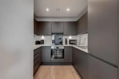 a kitchen with gray cabinets and a wooden floor at Huge Long Stay Savings! City View Balcony Penthouse in Liverpool