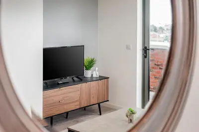 a living room with a flat screen tv on a dresser at Huge Long Stay Savings! City View Balcony Penthouse in Liverpool