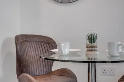 a glass table with two cups and a chair at Huge Long Stay Savings! City View Balcony Penthouse in Liverpool