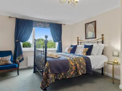 a bedroom with a bed with blue curtains and a window at Beautiful Detached Property Hot Tub Sauna - Pass the Keys in Lake Side