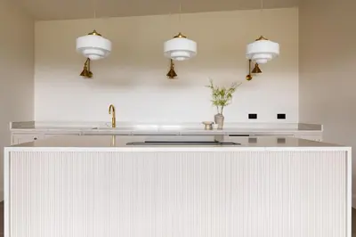a white kitchen with three pendant lights and a counter at The Lookout in Preston