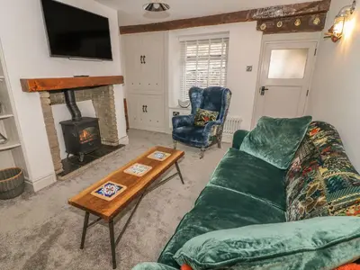 a living room with a green couch and a fireplace at Cockle Bay Cottage in Morecambe