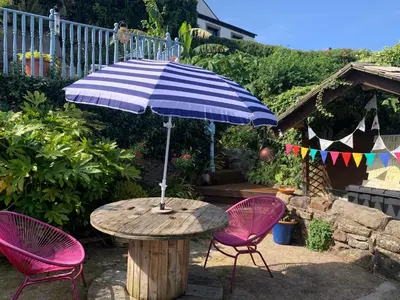 a table with an umbrella and two pink chairs at Cockle Bay Cottage in Morecambe