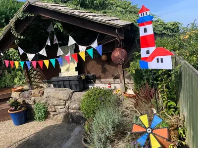 a small house with a lighthouse in a garden at Cockle Bay Cottage in Morecambe
